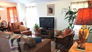 Ein Wohnzimmer mit Sofa, Sessel, Fernseher und Dekorationselementen.