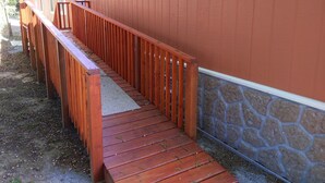 Eine Holzterrasse, die zu einem Gebäude mit steinernen Fundamenten führt.
