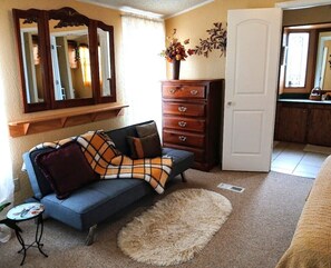 A room with a sofa, a dresser, a mirror, and a door. - Casual Comfort for Duners, Hunters, and Normal Folks (Waynoka)