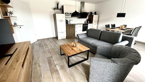 Una sala de estar moderna con un sofá gris, una mesa de centro de madera y un comedor con mesa y sillas.