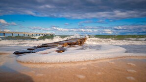 Un muelle que se adentra en el océano, con olas rompiendo contra él.