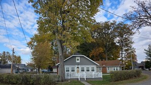 Ein eingeschossiges Haus mit Veranda, Garage und kleinem Garten.