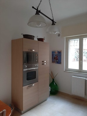 Una cocina con microondas integrado, horno y una lámpara colgante.
