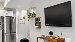 Eine moderne Küche mit Edelstahlgeräten, einem schwarzen Wand-Fernseher und einem Holztisch mit Dekoration.