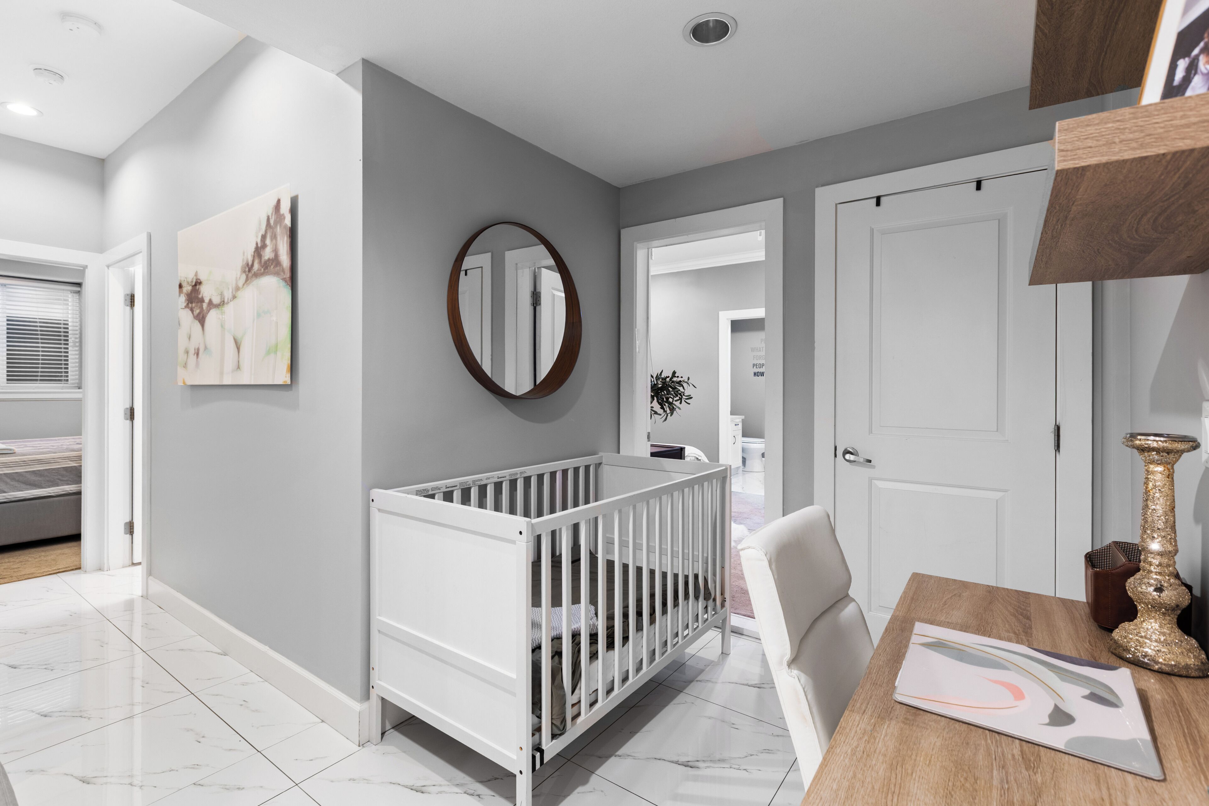 A modern baby room with a crib, a dining table, and a mirror on the wall.