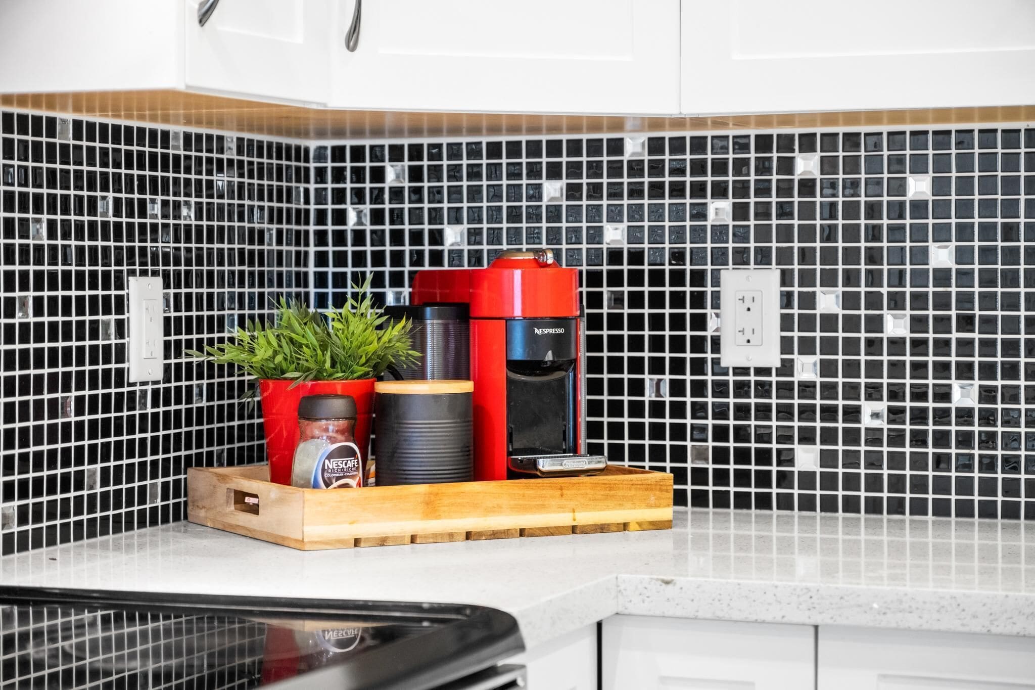 En køkkenbordplade med kaffemaskine, en potteplante og et kaffeglas.