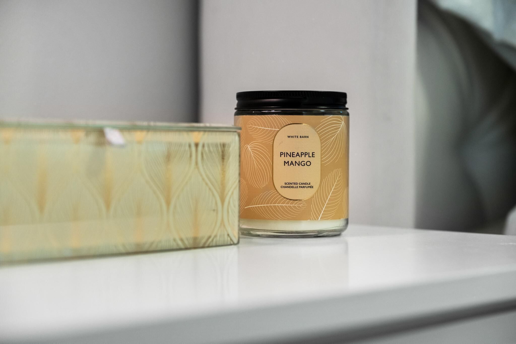 A scented candle labeled 'PINEAPPLE MANGO' on a white surface.