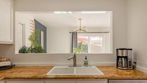 A kitchen with a white sink, granite countertop, and a coffee maker. - The Yorba Oasis w/Pool (Palm Springs)