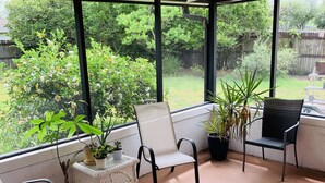 A covered patio with a ceiling fan, large windows, and potted plants. - Cush Jax Baymeadows Ranch, Close to Everything! (Jacksonville)