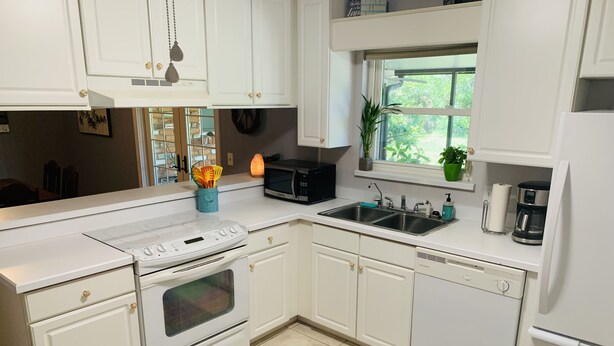 A modern kitchen with white cabinets, a built-in oven, a microwave, a sink, and a coffee maker. - Cush Jax Baymeadows Ranch, Close to Everything! (Jacksonville)