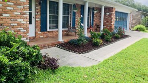 A brick house with a covered porch, a garage, and a well-maintained lawn. - Cush Jax Baymeadows Ranch, Close to Everything! (Jacksonville)