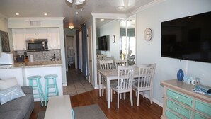 A spacious living area with a dining table, chairs, a sofa, and a kitchen with a microwave. - Oceanfront condo with beach view – 2 pools (Galveston)