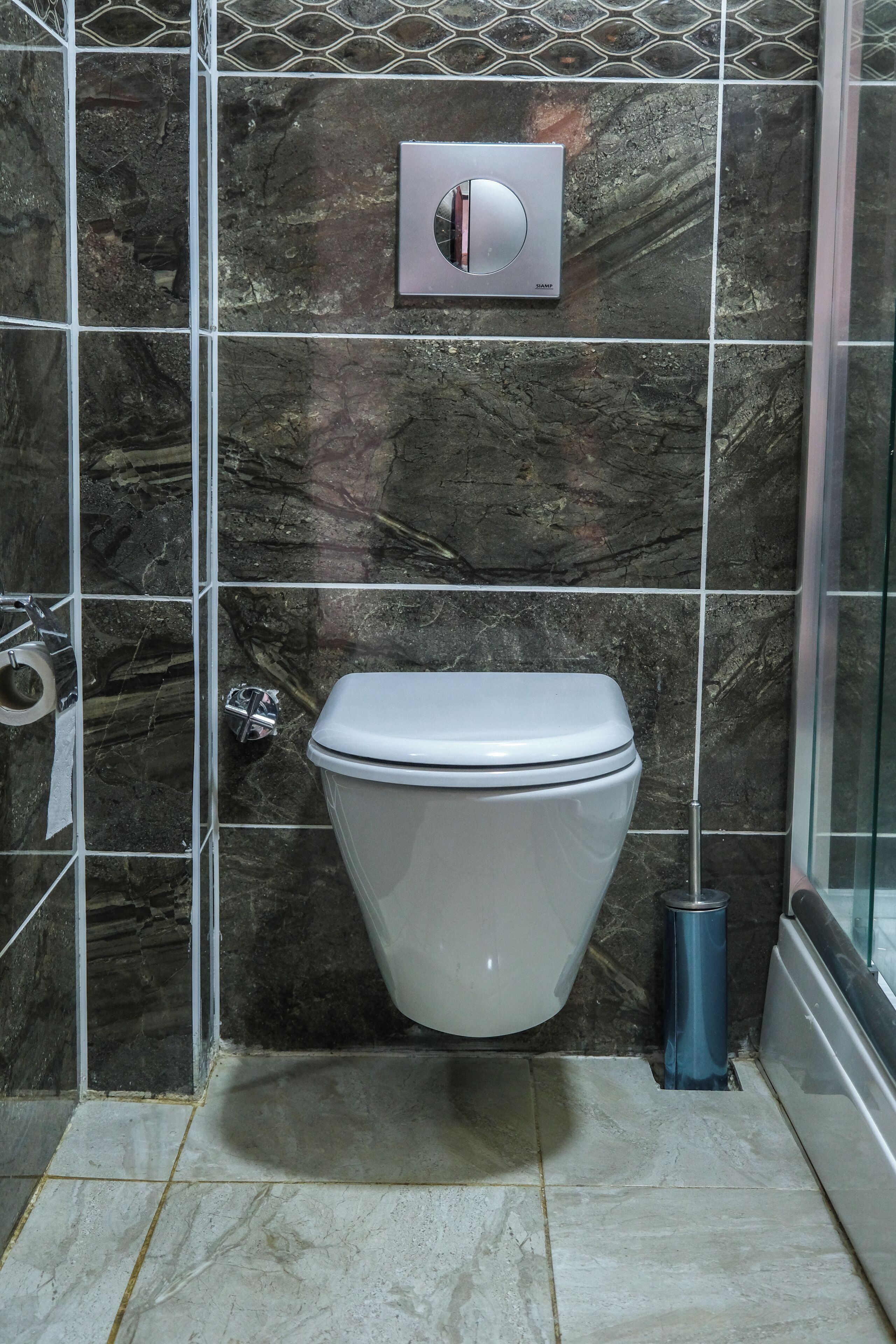 A bathroom with a toilet, a hand dryer, and a trash bin.