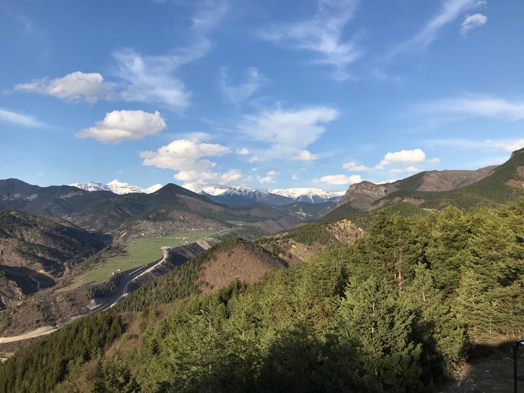 A mountainous landscape with a valley and a road.