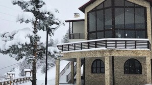 A two-story building with large windows and a balcony, surrounded by snow-covered trees. - Savsat Kosk Otel (Savsat)
