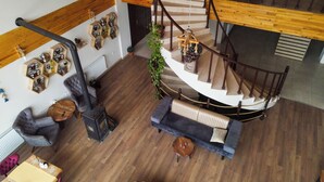 A multi-level interior with a wooden staircase, a sofa, a table, and a fireplace. - Savsat Kosk Otel (Savsat)
