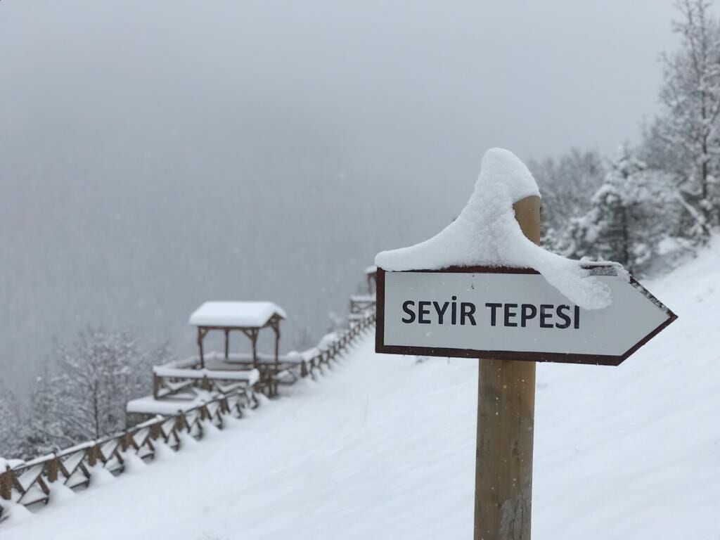 A signpost with the text "SEYİR TEPESI" in a snowy landscape.