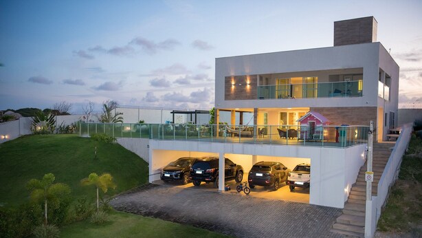 Une maison moderne à deux étages, dotée d’un garage fermé, d’un balcon et d’un escalier menant à l’étage supérieur.