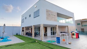 Une maison moderne à deux étages, dotée d’un patio, d’une piscine et d’un espace de jeux pour enfants.