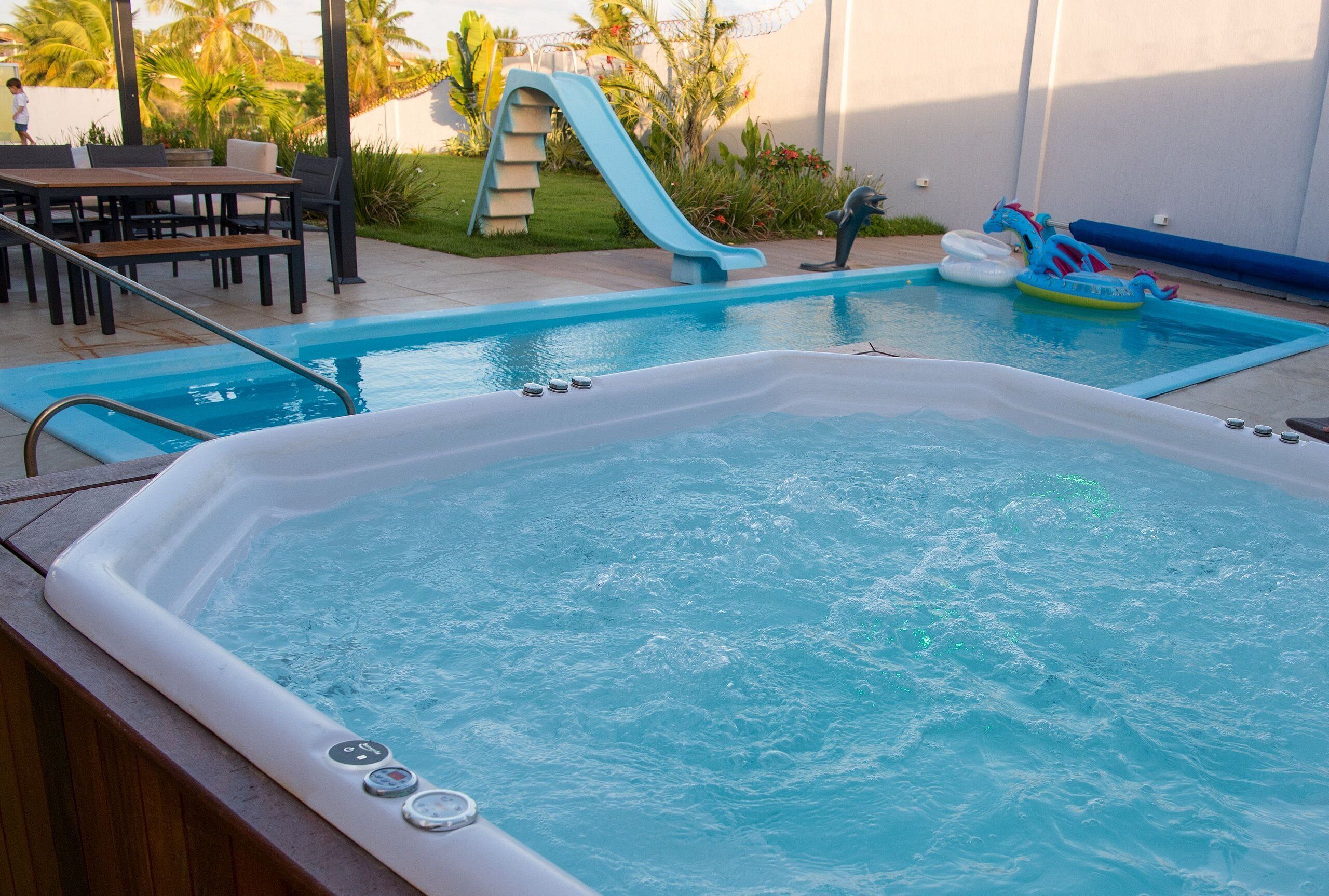 A swimming pool with a hot tub, a slide, and inflatable toys.