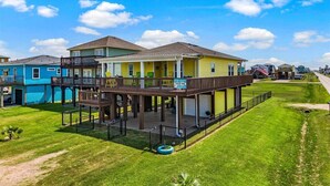 A two-story house with a deck, a 'For Rent' sign, and a lawn. - Great Location, Fenced Yard, Pet Friendly! Low Rate! (Surfside)
