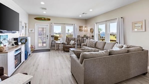 A spacious living area with a sofa, a television, and a fireplace. - Great Location, Fenced Yard, Pet Friendly! Low Rate! (Surfside)
