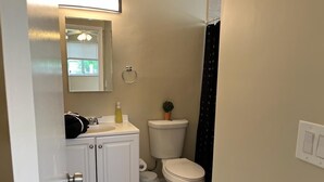 A bathroom with a white sink, toilet, and a small window with a view of greenery.