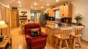 A cozy kitchen with wooden cabinets, a red armchair, and a bar area. - NEW!! Clean, Comfortable & Spacious Northwoods Cabin. (Florence)