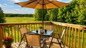 A wooden deck with a table and chairs, a potted plant, and a large umbrella. - NEW!! Clean, Comfortable & Spacious Northwoods Cabin. (Florence)