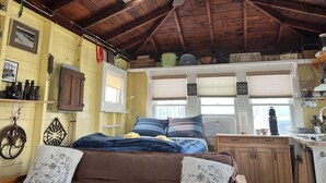 A cozy room with a sloped ceiling, a bed with blue bedding, a wooden cabinet, and a skylight.