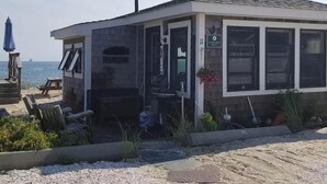 A beachside building with a covered patio area, a sign indicating a restaurant, and a view of the sea.