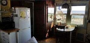 Enjoy a compact room with a kitchenette, wooden table, and ocean views from the window.