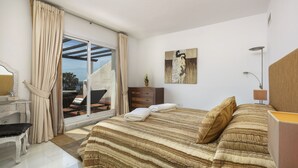 Een slaapkamer met een groot bed, een bureau en uitzicht op een terras.