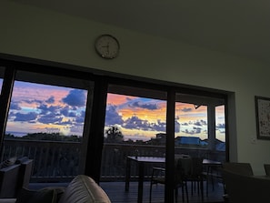 Enjoy a serene view of the water from the comfort of this room, featuring a large window and outdoor seating area.