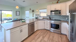 A modern kitchen with white cabinets, stainless steel appliances, and a large island. - Spectacular beach front views with a short walk to members only beach (Upper Captiva)