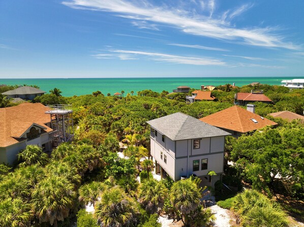 A coastal residential area with houses surrounded by lush greenery and a view of the ocean. - Spectacular beach front views with a short walk to members only beach (Upper Captiva)