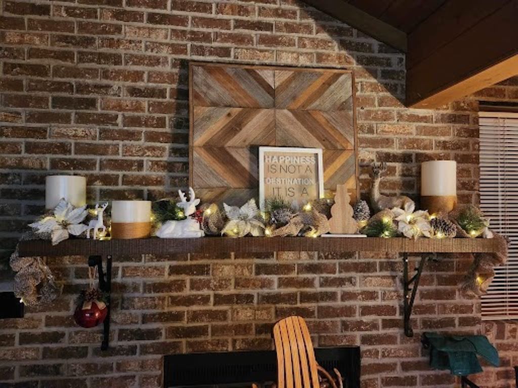 Une cheminée en briques surmontée d’une étagère décorée de bougies, d’une citation encadrée et de divers objets décoratifs.