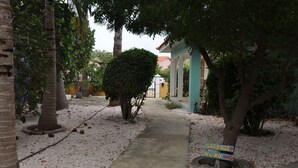 A pathway lined with trees and a sign indicating directions to 'Garbage' and 'Kilio'. - Casa Makoshi An oasis of tranquility in Divers Paradise (Hato)
