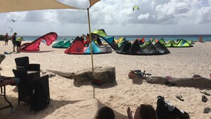 A beach with multiple colorful tents and chairs under a large canopy. - Casa Makoshi An oasis of tranquility in Divers Paradise (Hato)