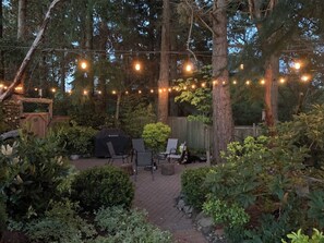 An outdoor patio area with string lights, a grill, and seating. - A private suite overlooking a lake, 20 mins from the city, and no pet fee! (Victoria)