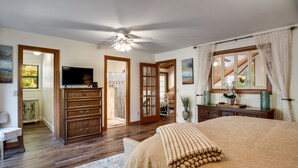A bedroom with a large bed, wooden dresser, and a television.