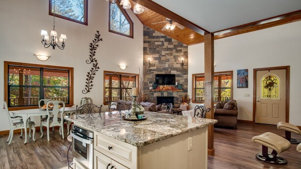 A spacious kitchen with a large island, a stone fireplace, and a dining area with a view of the outdoors.