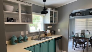 A kitchen with teal cabinets, a white countertop, and a dining area with a table and chairs.