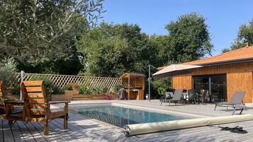 Relax by the serene pool surrounded by lush greenery and a wooden fence.