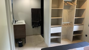 A modern bathroom with a sink, towel rack, and a walk-in closet with multiple shelves and hangers.