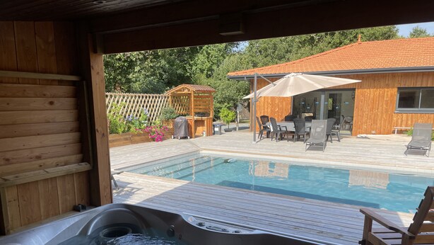 A wooden deck with a hot tub and a swimming pool.