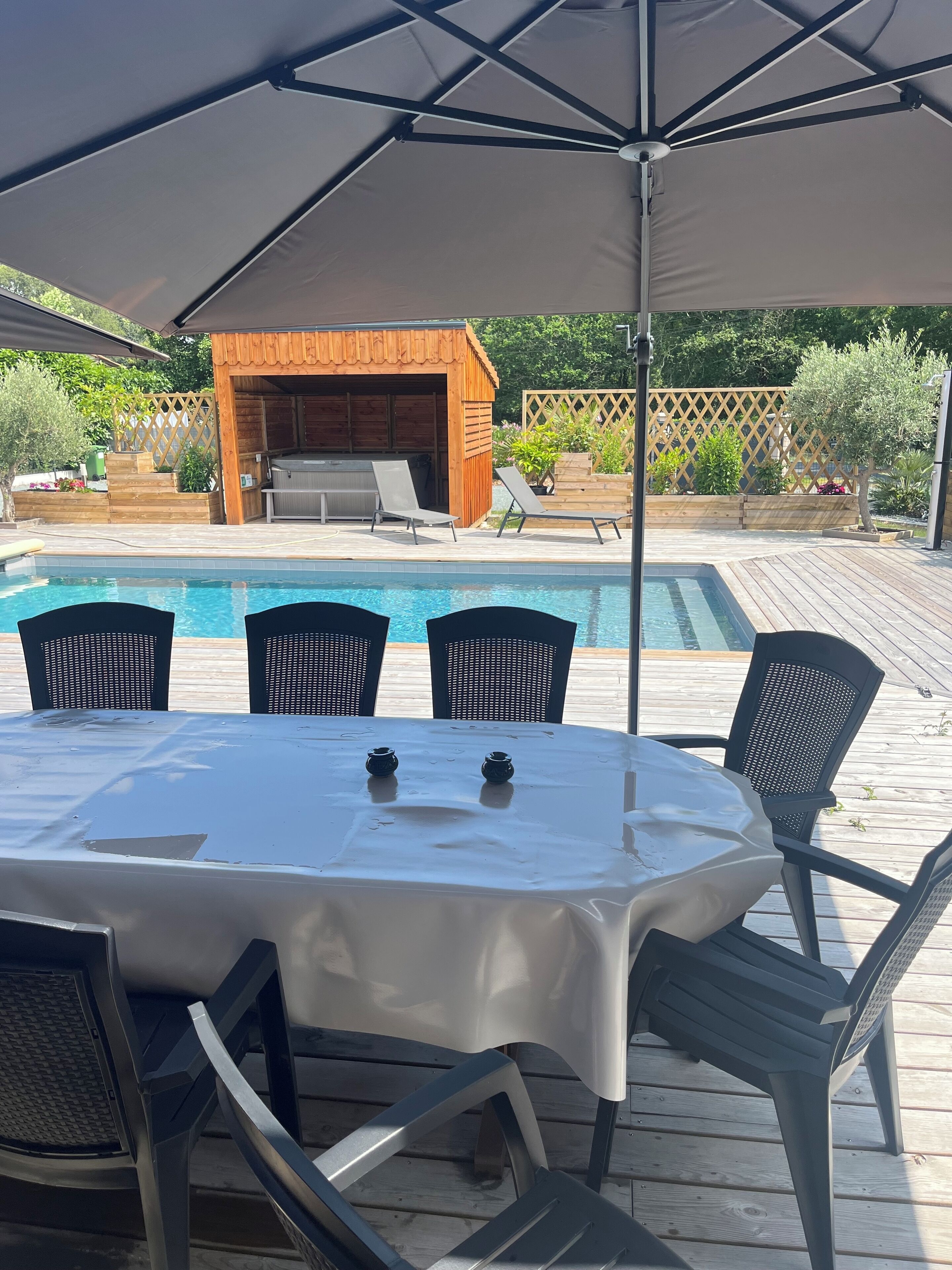 A covered outdoor area with a pool, a barbecue area, and a table with chairs.