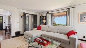 Ein modernes Wohnzimmer mit einem Ecksofa, einem Glastisch und einem Bücherregal.