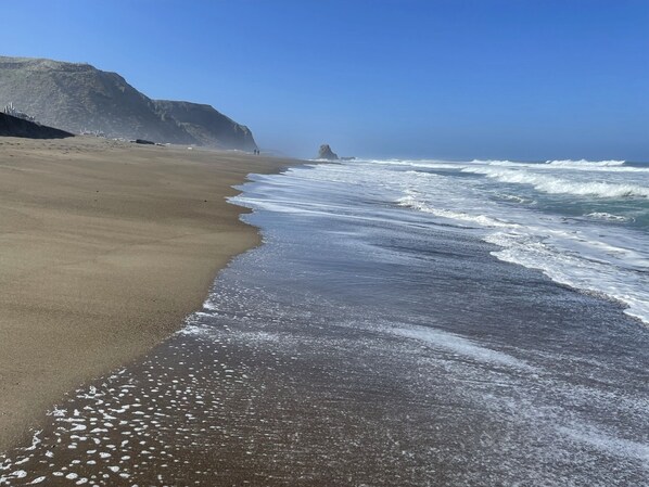 Una playa con un acantilado rocoso y olas.