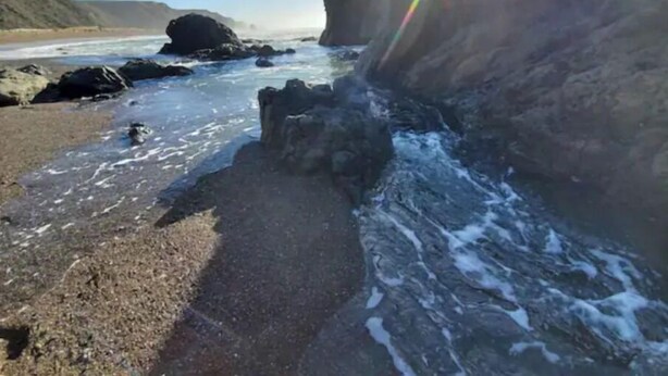 Ein felsiger Strand mit brechenden Wellen.